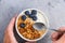 Healthy breakfast food with granola, yogurt, fruits, nuts and chia seeds. Male hands holding spoon above breakfast bowl