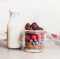 Healthy breakfast in glass making with oatmeal , Chia seeds, Goji berries, fresh berries and bottle of milk , front view