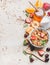 Healthy breakfast ingredients. Oat granola in bowl with nuts, strawberry and mint leaves, pitcher, honey in jar, fresh