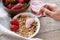 Healthy breakfast. Muesli and yogurt with strawberries. A woman`s hand puts a spoonful of yogurt in the muesli