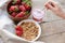 Healthy breakfast. Muesli and yogurt with strawberries. A woman`s hand puts a spoonful of yogurt in the muesli