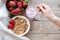 Healthy breakfast. Muesli and yogurt with strawberries. A woman`s hand puts a spoonful of yogurt in the muesli