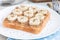 Healthy breakfast sandwich with crunchy peanut butter, banana and chia seeds, on white plate, horizontal, closeup