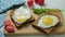 Healthy Breakfast: scrambled eggs on slices of whole-grain bread with arugula and tomatoes on a wooden Board