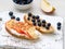 Healthy breakfast with sweet sandwiches - ricotta, blueberries, apple slices, peanut butter on white rustic wood table