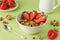 Healthy breakfast in a white bowl with homemade baked muesli, nuts, fresh strawberries, on a green background. Natural granola