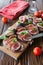 Healthy bruschettas with bread, cream cheese, prosciutto, figs and basil on rustic wooden table