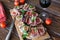 Healthy bruschettas with bread, cream cheese, prosciutto, figs and basil on rustic wooden table