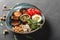 Healthy Buddha bowl dish with avocado, tomato, cheese, chickpea, fresh arugula salad, baked potatoes and sauce pesto on background