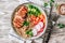 Healthy buddha bowl lunch with grilled chicken, quinoa, cucumber, radish, carrots on white wooden background.