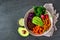 Healthy Buddha bowl with rapini, quinoa, sweet potato, chickpeas and avocado, top view scene over dark slate