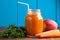 Healthy carrot apple smoothie in a jar on blue wooden background