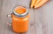Healthy carrot smoothie in a jar with tube wooden