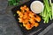 Healthy cauliflower buffalo wings with celery and ranch dip, top view over dark slate