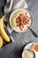 Healthy cereal breakfast, oatmeal topped with banana slices, dried cranberries, walnut, served with honey