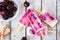Healthy cherry yogurt popsicles table scene over rustic white wood