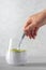 Healthy chia pudding made with avocado and seeds, hand with spoon. White background.