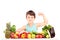 Healthy child showing his arm muscles and sitting on a table full of pile of fruits and vegetables