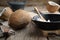 Healthy coconut oil for cooking on frying pan. Coconuts on kitchen table