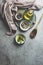 Healthy cooking ingredients on grey concrete kitchen table: olive oil, sage, garlic, pepper, salt, wooden cooking spoon, dish