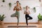 Healthy couple mom and little girl doing yoga one leg stand on yoga mat at home.Mother and female daughter practice yoga breathing