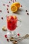 Healthy cranberry tea in a glass with fresh lemons on the gray concrete background