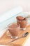 Healthy delicious chocolate yoghurt pudding serving two cups wooden cutting boarding. Selective focus