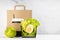 Healthy daily diet plan - set of cup of coffee, salad with avocado, egg, apple, paper packaging in white interior. Advertising.
