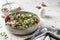 Healthy diet salad with feta cheese, arugula, mushrooms, walnut in ceramic bowl on textured background with text space