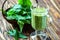 Healthy eating, drinks and diet concept. Beautiful appetizer green smoothie or spinach juice in glass jar with fresh leaves on woo