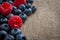 Healthy eating and fresh berry fruits with closeup on mixed blueberries and raspberries spilled on burlap background and copy