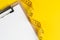 Healthy eating plan, diet or fitness planning, blank white paper on clipboard with measuring tape on solid yellow background,