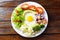 Healthy eating plate of avocado salad with eggs and vegetables over rustic wooden table. Ketogenic and Paleolithic Diet