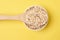 Healthy eating. Wooden spoon. Oat flakes. Yellow background