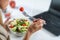 Healthy eating at work. Woman indulges in a delightful fresh salad at her workplace. With every bite, she embraces the nourishing