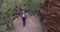 Healthy elderly lady hiking through red sandstone canyon with trekking staffs
