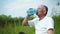 Healthy elderly man restores balance and drinks clean water from a bottle for sports nutrition after playing sports or