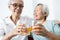 Healthy elderly sibling drinking vitamin C,orange juice and clinking glasses at home,senior people with effervescent vitamin C,