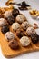 Healthy energy balls of nuts, oatmeals and dried fruit with coconut, flax and sesame seeds on wooden board on a white background,