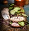 Healthy fish sandwich with herring, cucumber and sprouts on rustic kitchen table