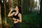 A healthy fitness girl stands and drinks water from a transparent bottle in the forest. Fitness watch on hand