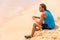 Healthy fitness man drinking detox juice drink on beach run. Runner athlete relaxing on training break with juice smoothie for