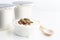 Healthy flavored yogurt in plastic cup and ceramic bowl with cereal and wooden spoon isolated on the white background. With copy