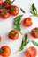 Healthy food background - raw tomatoes and wild herbs on white background, vibrant colours