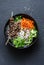 Healthy food bowl - beef skewers, rice noodles and vegetable salad on dark background