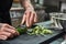 Healthy food. Close up of male hands with beautiful tattoos peeling cucumber for salad while standing in a restaurant