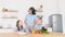 Healthy food. Happy family of mother and children preparing vegetable salad in kitchen.