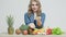 Healthy food at home, woman in the kitchen with fresh vegetables and fruits on a white wall background