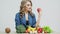 Healthy food at home, woman in the kitchen with fresh vegetables and fruits on a white wall background