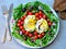 Healthy food on a plate. Rucola, avocado with egg, cherry tomatoes, blue onion. Vegetarian lunch.